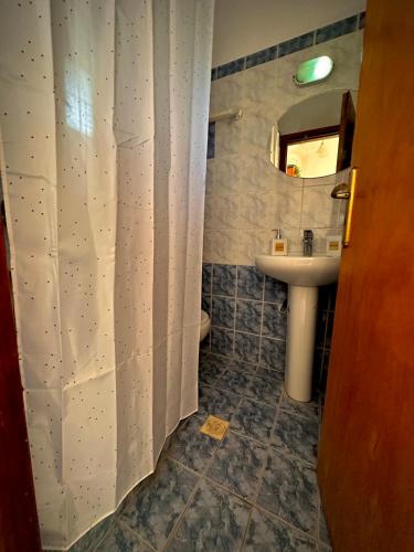a bathroom with a white shower curtain and a sink at Katerina Apartments in Lefkimmi