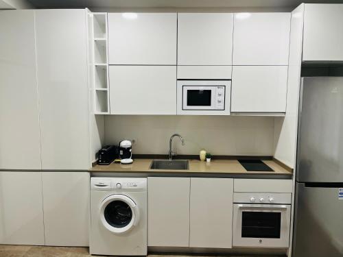 uma cozinha com armários brancos e uma máquina de lavar e secar roupa em Villa Mercedes em Toledo