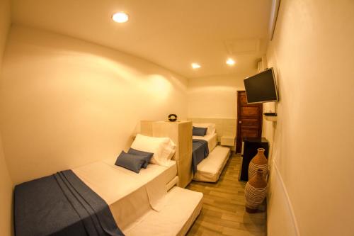 a small room with two beds and a tv at Santa Alejandría Hotel in Cartagena de Indias