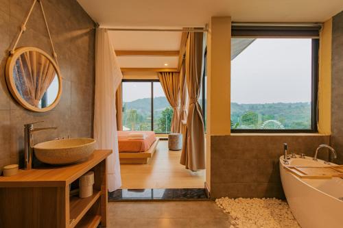 a bathroom with a tub and a sink and a bed at Melody Retreat - Venuestay in Hòa Bình