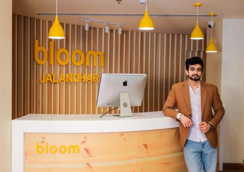 a man standing in front of a desk with a computer at Bloom Hotel - Jalandhar in Jalandhar