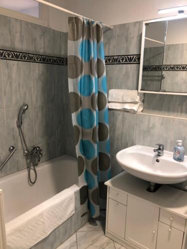 La salle de bains est pourvue d'un lavabo, d'une baignoire et d'une douche. dans l'établissement Cozy Appartment with Balcony, à Friedrichshafen