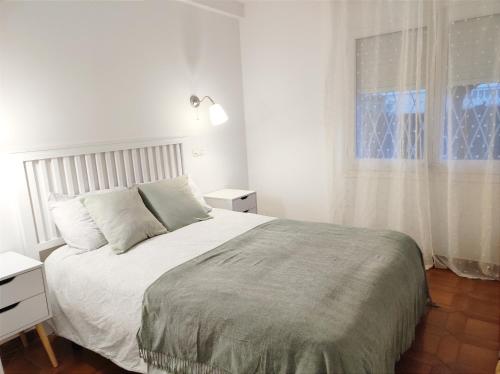 a white bedroom with a bed and a window at Apartament familiar tranquil a Platja d'Aro in Platja  d'Aro