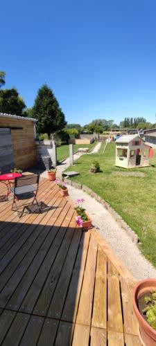 a wooden deck with a bench and a picnic table at Chez Marie à 5kms de St Valery sur Somme in Pendé