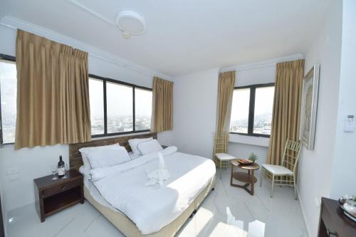 a bedroom with a large white bed and windows at Haifa Peak in Haifa
