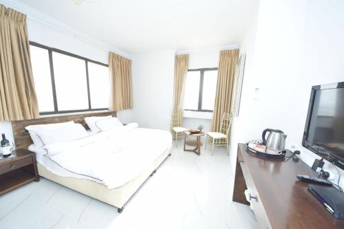 a white bedroom with a bed and a tv at Haifa Peak in Haifa