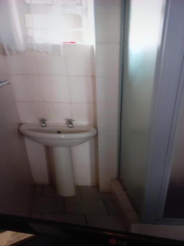 a bathroom with a white sink and a window at Amanzimtoti Beachfront Holiday Apartment , Flat No 23, Ezulweni in Durban