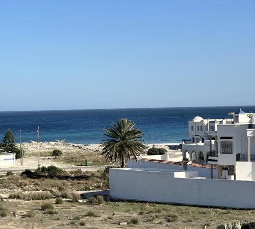 a building with a palm tree and the ocean at Luxury 3 Bedrooms Apartment Sea View in Rejiche