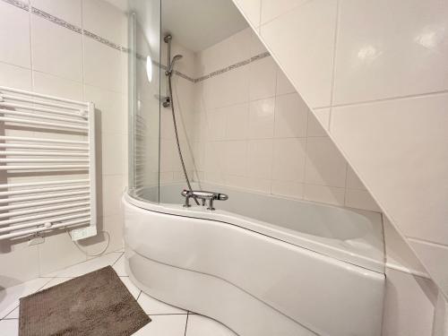 y baño de azulejos blancos con bañera blanca. en Maison La Madeleine hyper centre, en Vendôme