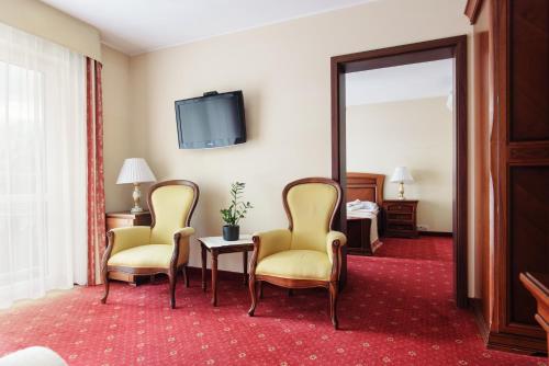 a hotel room with two chairs and a mirror at Lila Medical SPA in Ciechocinek