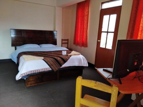 a bedroom with a bed and a desk with a television at Hostal Casa del Montañista in Huaraz