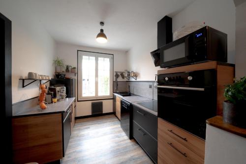 a kitchen with a black stove top oven next to a window at Zénithouse in Éterville