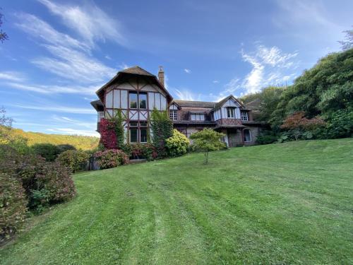 une grande maison sur une colline avec une cour verdoyante dans l'établissement Le Manoir by CauxCottes, à Vattetot-sur-Mer