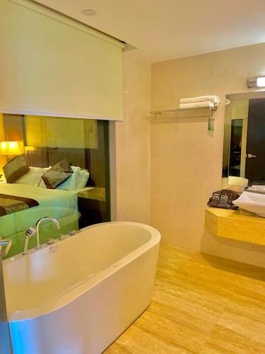 a bathroom with a bath tub and a bed at Royale Signature Hotel in Alor Setar