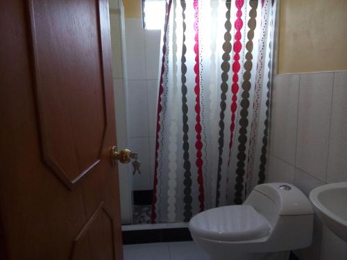 a bathroom with a toilet and a shower curtain at Hostal Casa del Montañista in Huaraz