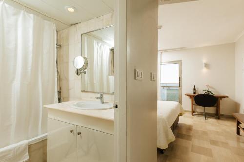a bathroom with a sink and a bed and a mirror at Residence Beach Hotel in Netanya