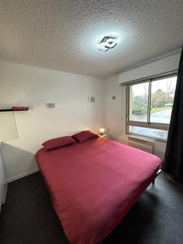 a bedroom with a large red bed with a window at Les Logis de Paray Appartement n1 in Paray-le-Monial