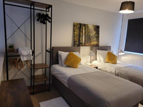 um quarto com 2 camas e almofadas amarelas em Rent Unique the Otford modern home 1 bed with mezzanine em Crawley
