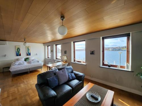 a living room with a couch and a bed and windows at Grannys Harbour View - 1st floor in Sønderborg