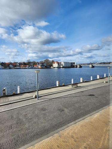 a road next to a body of water with a bridge at Grannys Harbour View - 1st floor in Sønderborg