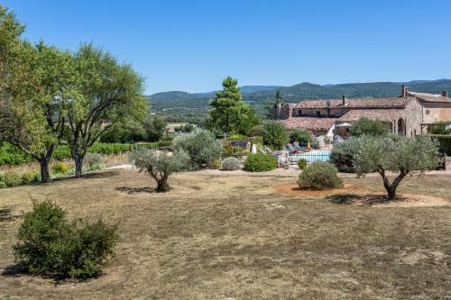 a garden with trees and a house in the background at Gîte Coquelicot in Gargas