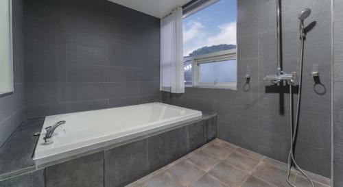 a bathroom with a bath tub and a window at Hinokki Haesuzzim Resort in Geoje 