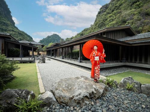 a woman standing on a rock holding an umbrella at Yoko Onsen Quang Hanh in Cẩm Phả