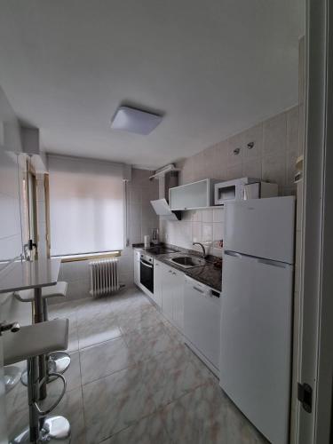 cocina con electrodomésticos blancos y nevera blanca en Vivienda SILVIA RENFE en León