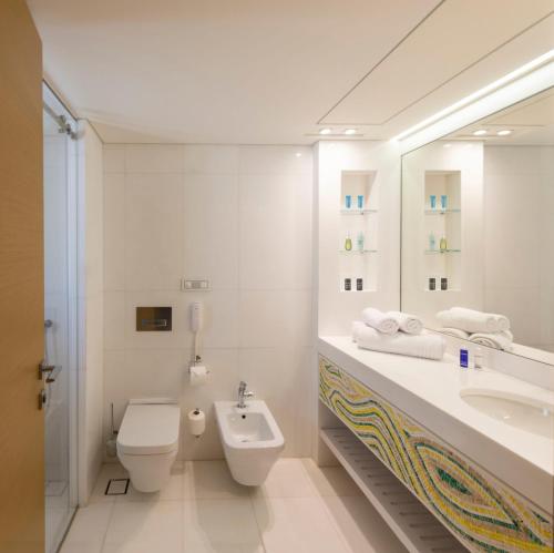 a white bathroom with a sink and a toilet at Domes Miramare, a Luxury Collection Resort, Corfu - Adults Only in Moraitika