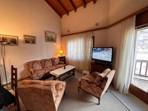 a living room with a couch and a tv at Domaine des Bains de Saillon in Saillon