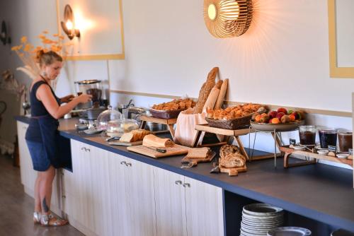 a woman standing in a kitchen with a buffet of food at Logis Hôtel Restaurant Le Chêne Vert in Rocher