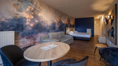 a hotel room with a table and a bed at Fletcher Hotel Restaurant Zeeduin in Wijk aan Zee