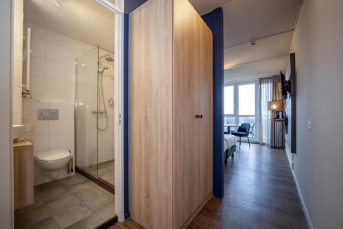 ein Bad mit einer Dusche und einem WC in einem Zimmer in der Unterkunft Fletcher Hotel Restaurant Zeeduin in Wijk aan Zee