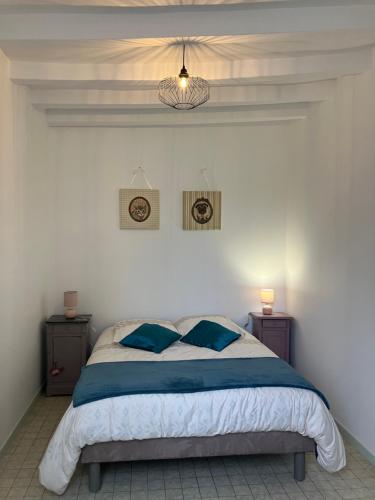 a bedroom with a bed with blue pillows on it at Gîte les Tilleuls in Le Guédéniau