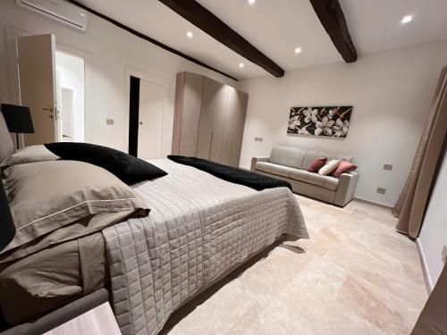 a bedroom with a large bed and a couch at Mia Margot Suite Apartment in Castagneto Carducci