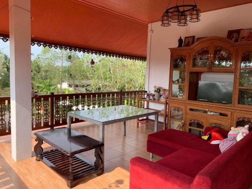 ein Wohnzimmer mit einem Sofa und einem Tisch in der Unterkunft บ้านต้นยางคาเฟ่ โฮมสเตย์ ลอร์ด 