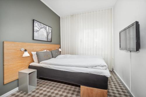 a bedroom with a bed and a flat screen tv at Ibsens Hotel in Copenhagen