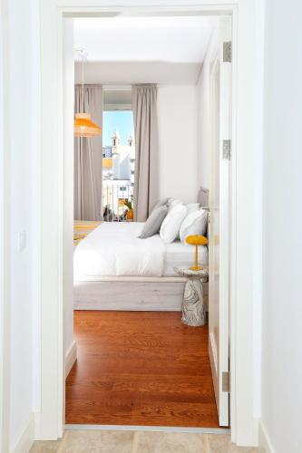 a bedroom with a white bed and a wooden floor at Salty Spot Apartment in Faro