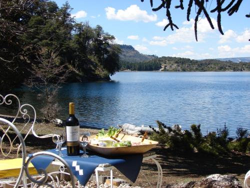 a table with a bowl of food and a bottle of wine at Cabañas Bahiamia in Villa Pehuenia