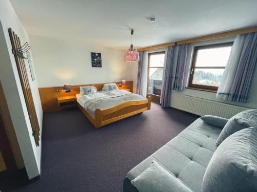 ein Schlafzimmer mit einem Bett und einem Sofa in der Unterkunft Hotel-Gasthof Lammersdorf in Millstatt