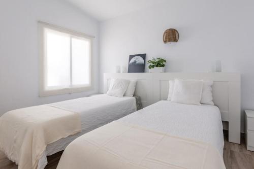 Dos camas en una habitación blanca con ventana. en Coastal Vista: retreat in nature, en Bajamar