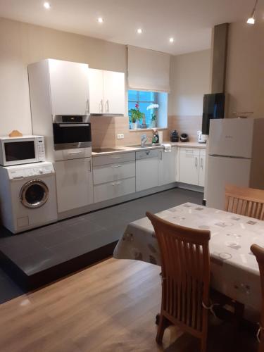 a kitchen with white cabinets and a table and a microwave at Wenceslas Cobergher Appartement II in Boutersem