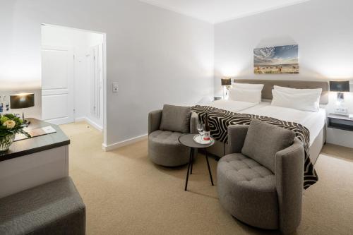 a hotel room with a bed and two chairs at Hotel Bellevue in Timmendorfer Strand