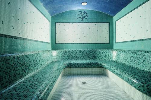 a bath room with a swimming pool in a room with tiles at Lila Medical SPA in Ciechocinek