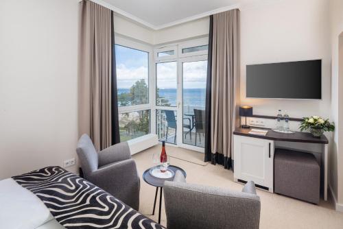 a living room with a bed and a large window at Hotel Bellevue in Timmendorfer Strand