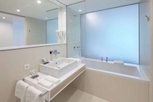 a bathroom with two sinks and a mirror and a tub at Hotel Nox in Ljubljana