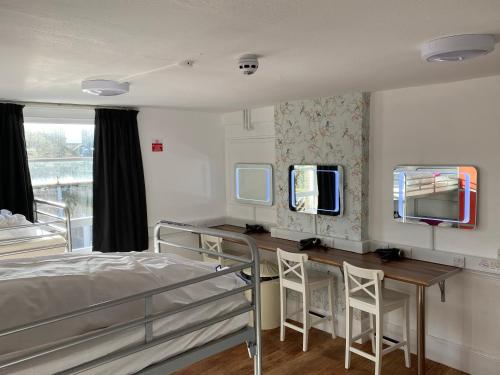 Bath YMCA Hostel في باث: غرفة نوم بسرير ومكتب ومرآة