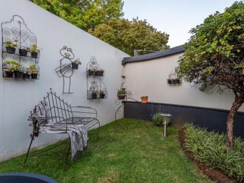 a garden with a chair and a wall with plants at Magnolia Guesthouse in Alberton