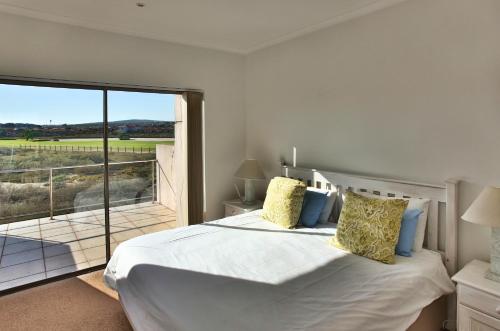 a bedroom with a large bed and a balcony at Mulligan in Langebaan