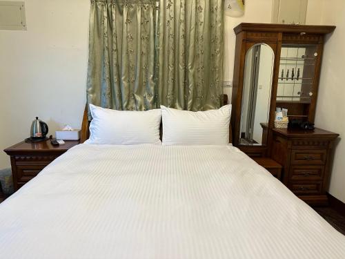 een slaapkamer met een groot wit bed en een spiegel bij 偕安民宿 in Hualien